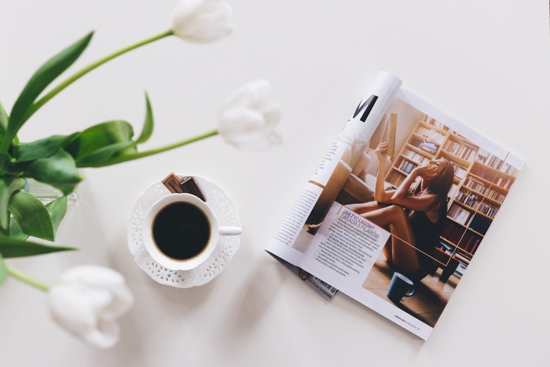 Majalah terbuka dan secangkir kopi dilihat dari atas